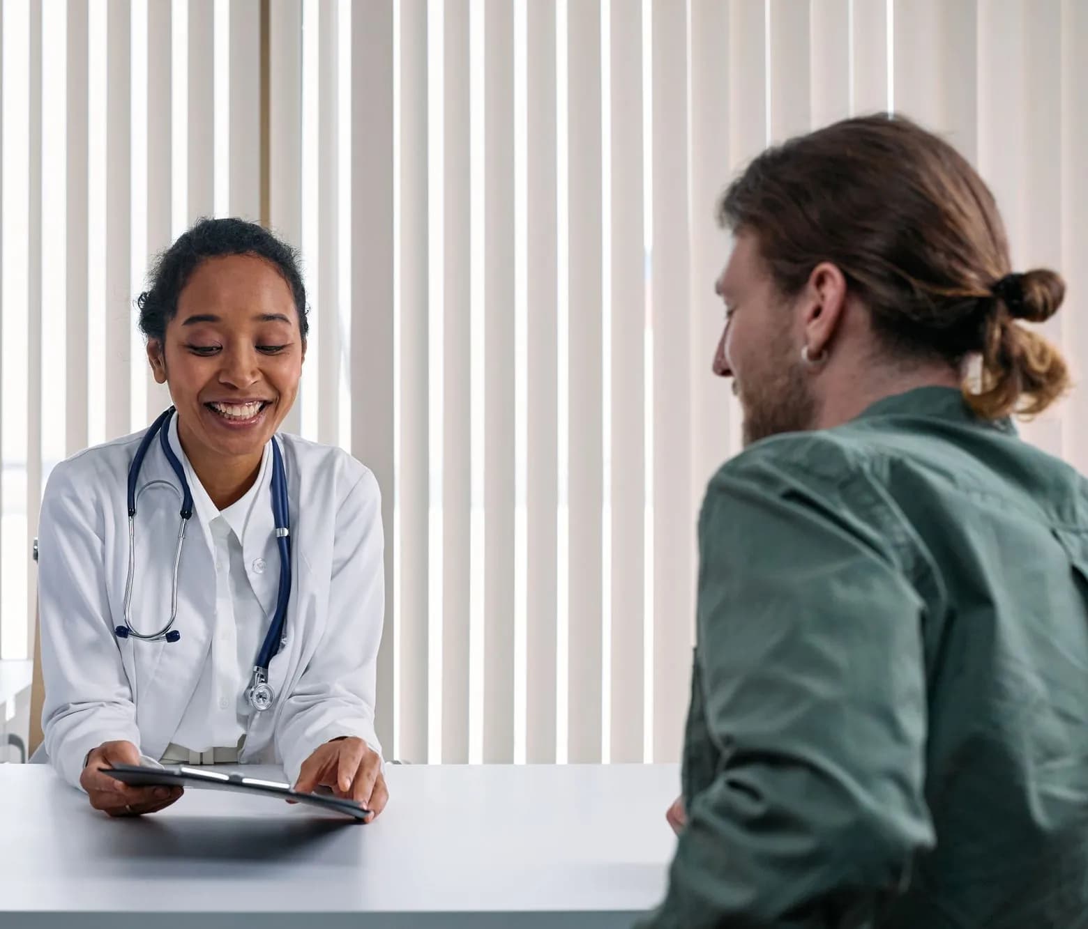 Clinician smiling and listening to a patient across a desk